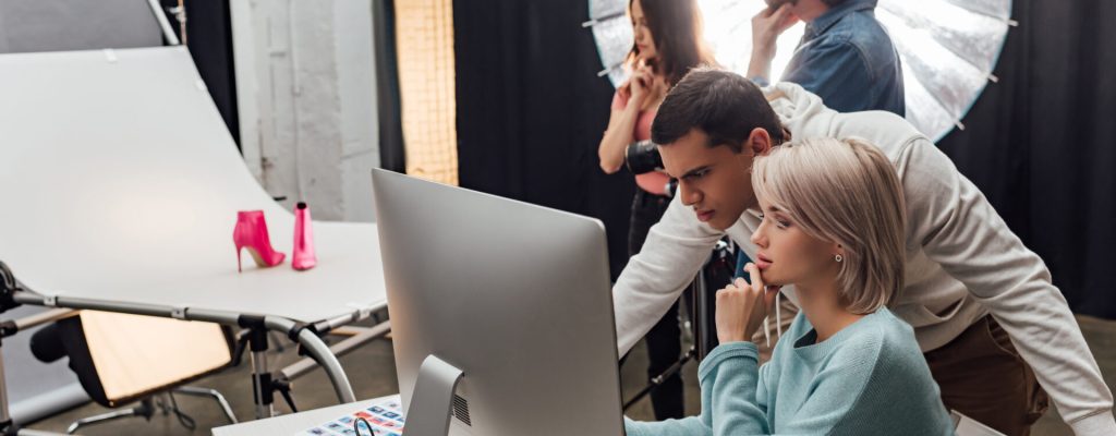 selective focus of coworkers looking at computer monitor in photo studio